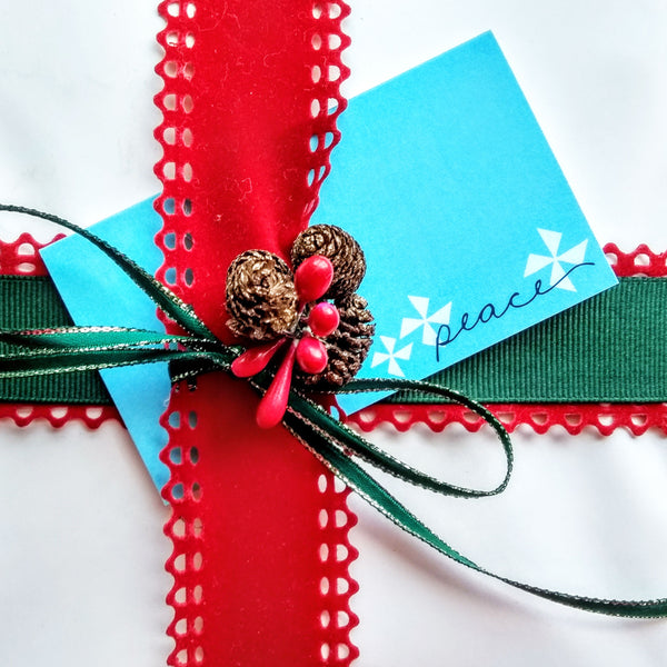 Five Patch Design Holiday gift enclosure shown on gift with ribbons
